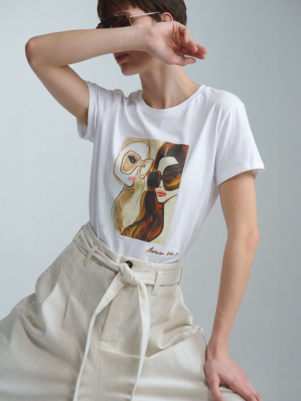 Exklusives weißes Damen-T-Shirt aus der limitierten RAILIN x Astrid Vos X Art Edition. Der hochwertige, aufwändige Art Print zeigt eine vom Retro-Chic inspirierte Modeillustration zweier Frauen mit markanten Sonnenbrillen als tragbares Kunstwerk.